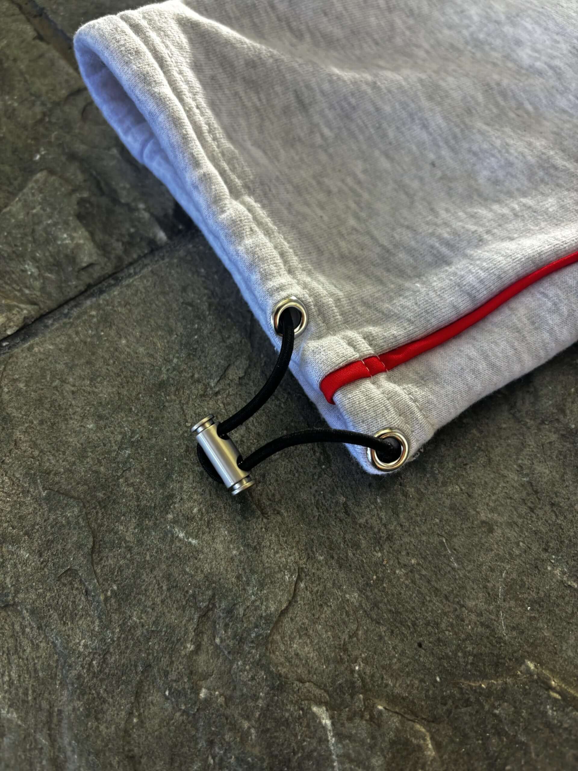 Detail of Allure Track Pants showing adjustable drawstring with chrome accents and red stripe.