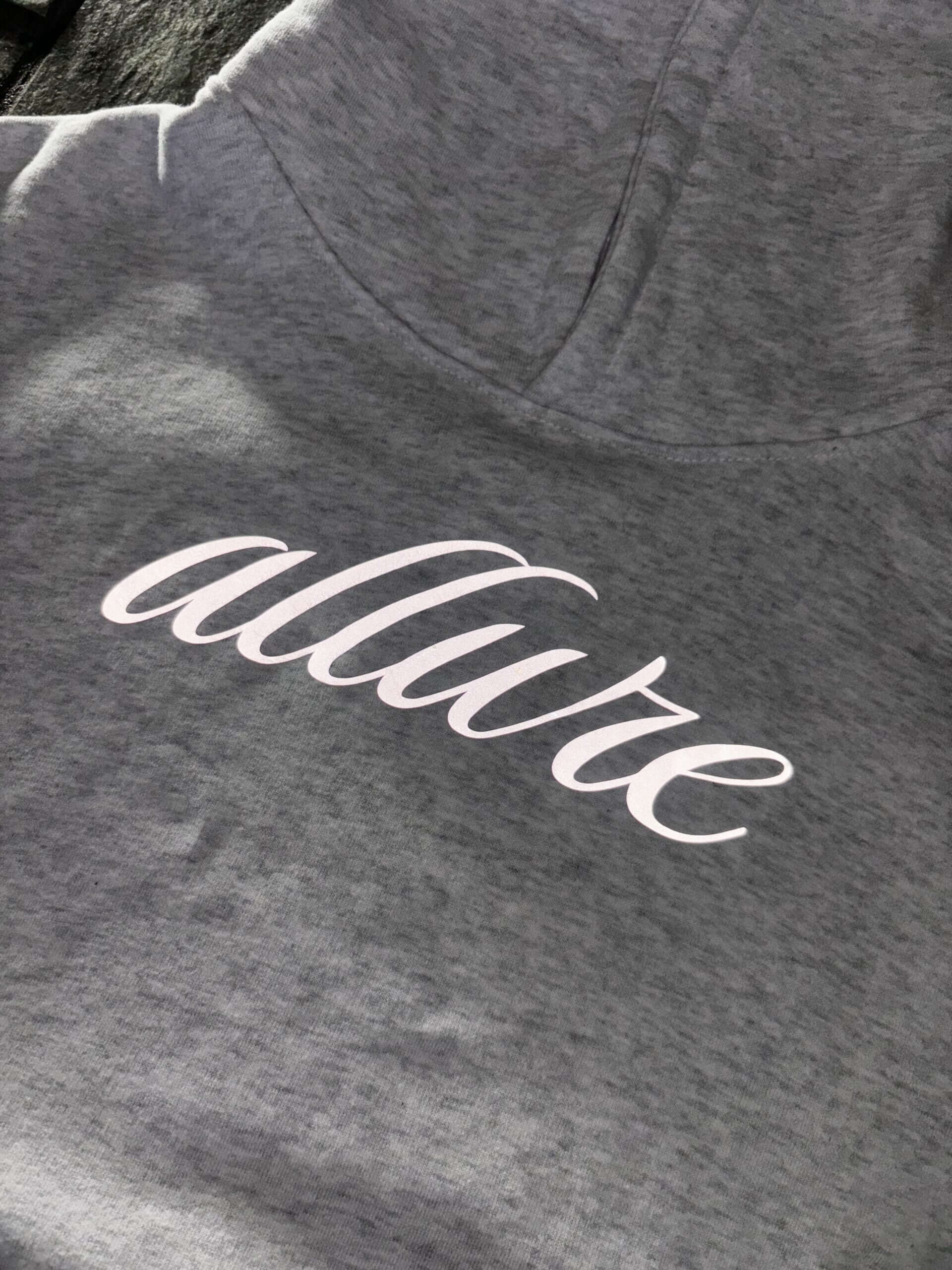 Close-up of Allure Reflective Hoodie showing luxurious grey fabric and reflective print design.